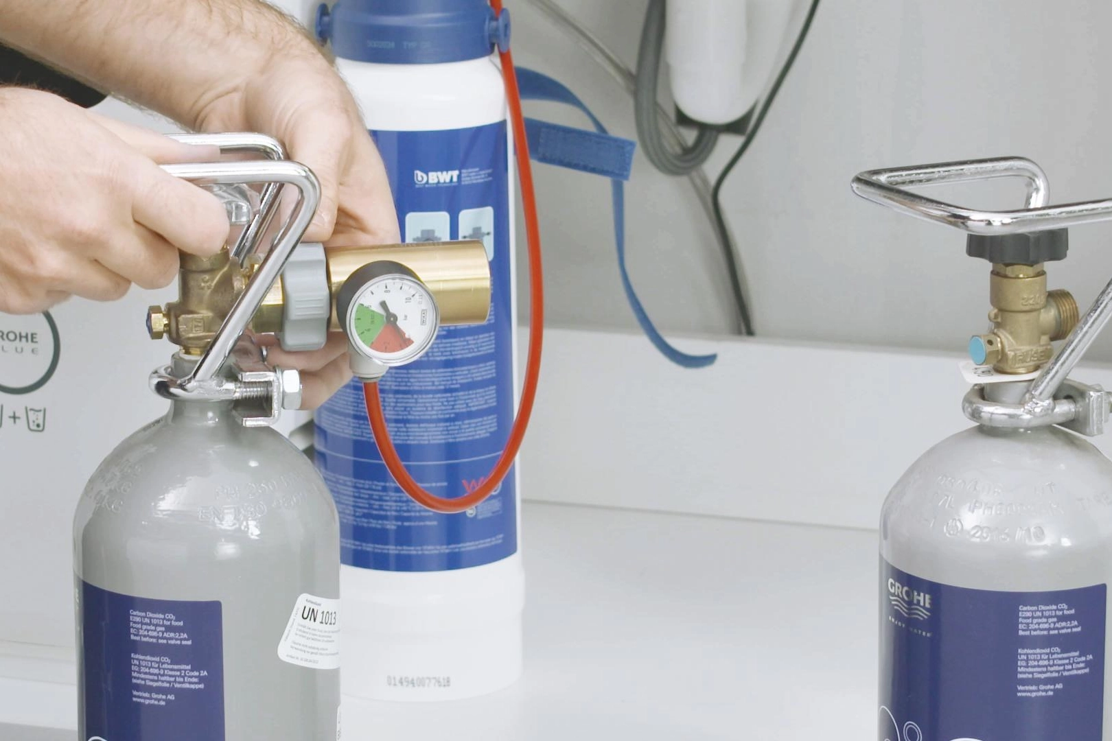 Hands replacing a white filter cartridge inside a tidy under-sink cabinet